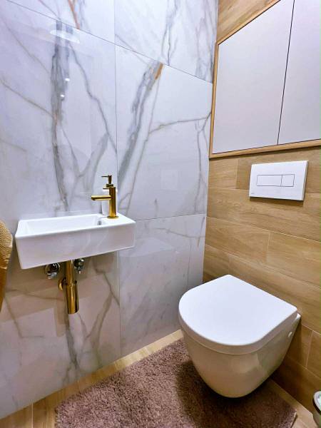 Koupelna s keramickým umyvadlem, zrcadlem a podlahou s dřevěným dekorem v 3-pokojovém bytě.