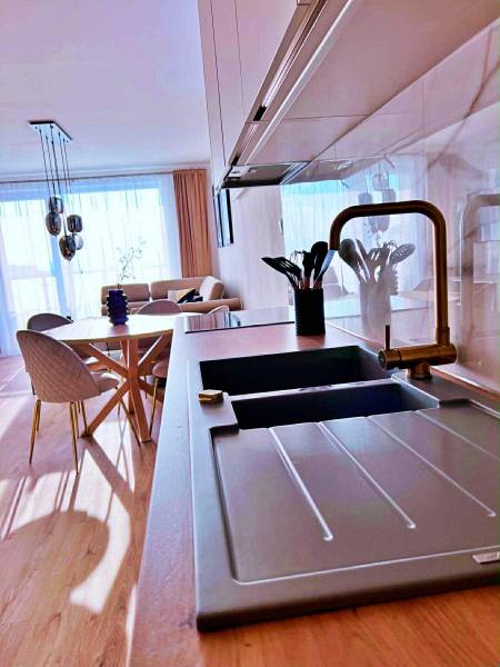 Kuchyně v 3-pokojovém bytě se světlou podlahou s dřevěným dekorem a stylovým sezením.