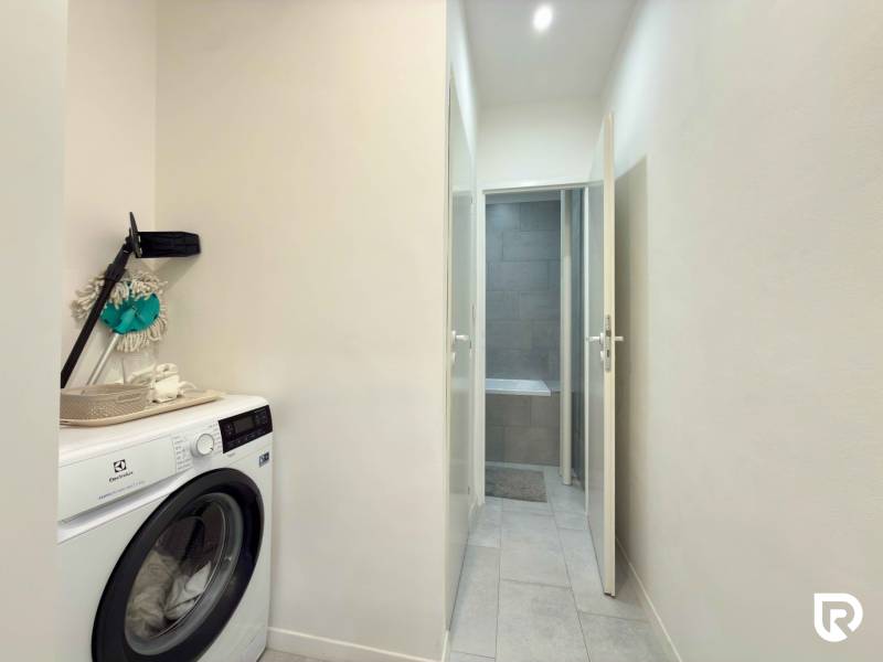 Pračka na chodbě 2pokojového bytu s přístupem do koupelny.