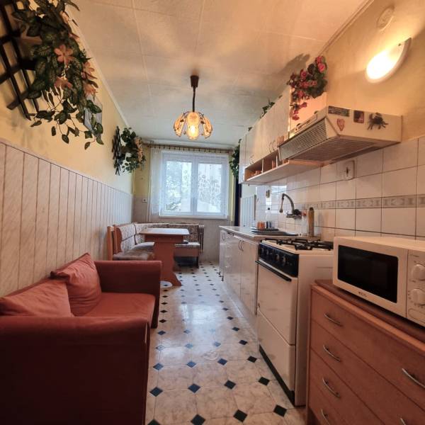 Kuchyně v 3-pokojovém bytě s jídelním koutem, pohovkou a vzorovanou podlahou.