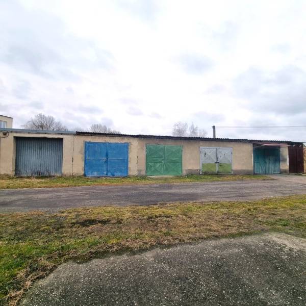 Budova se sérií pestrých garážových vrat v Kuklově, vedle asfaltové cesty.