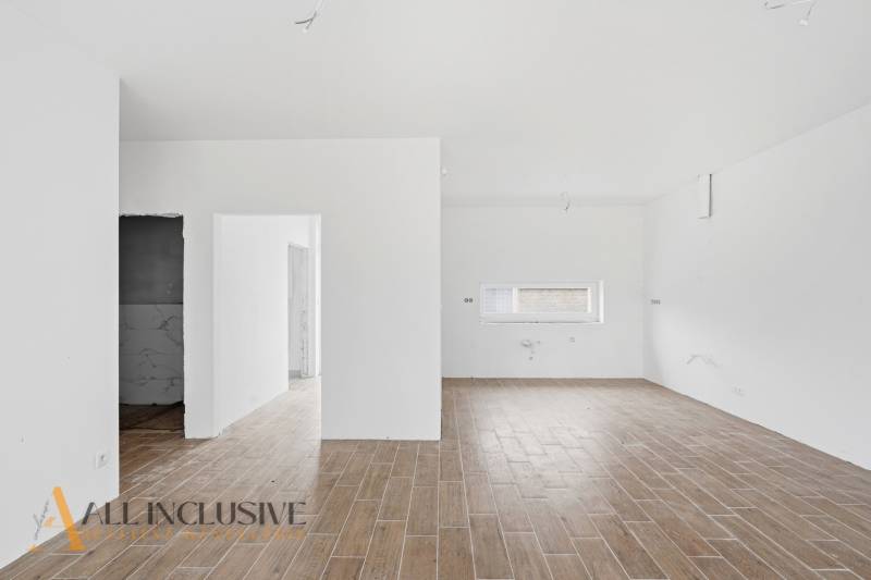 Interiér rodinného domu s podlahou s dřevěným dekorem a bílými stěnami.