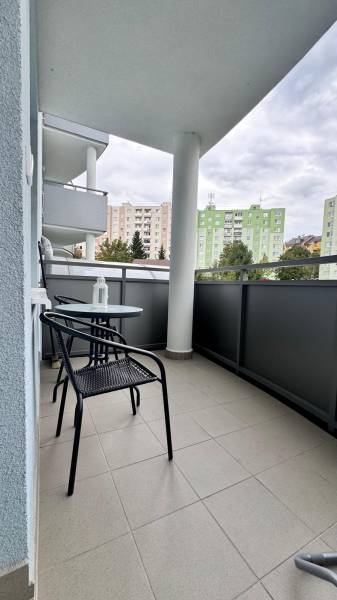 Balkon 2-pokojového bytu na Halalovce v Trenčíně se stolem a židlemi, výhled na paneláky.