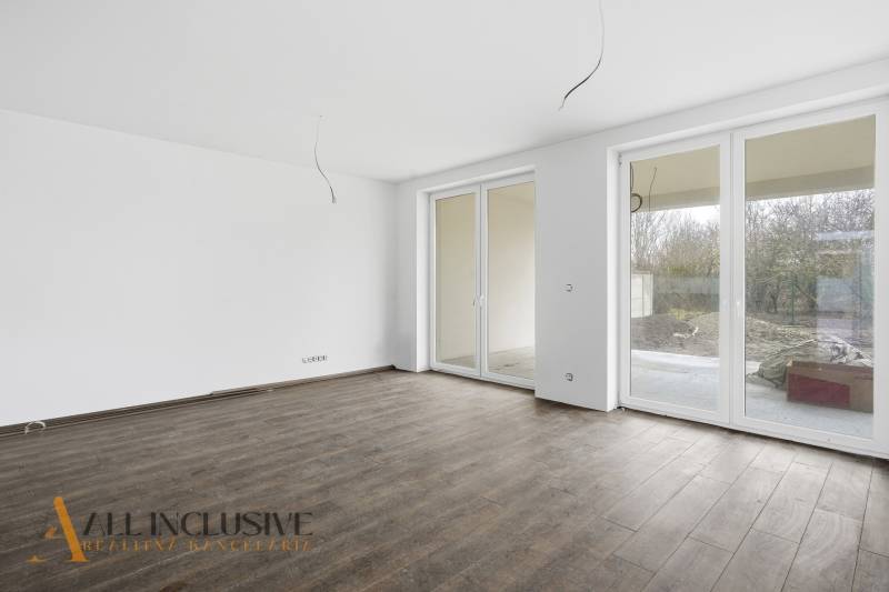 Prostorný pokoj v rodinném domě s velkými okny a podlahou s dřevěným dekorem.