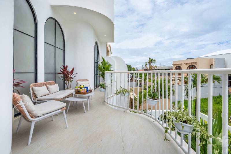 Prostorný balkon ve vile s pohodlným posezením, rostlinami a výhledem na Berawa v Canggu.