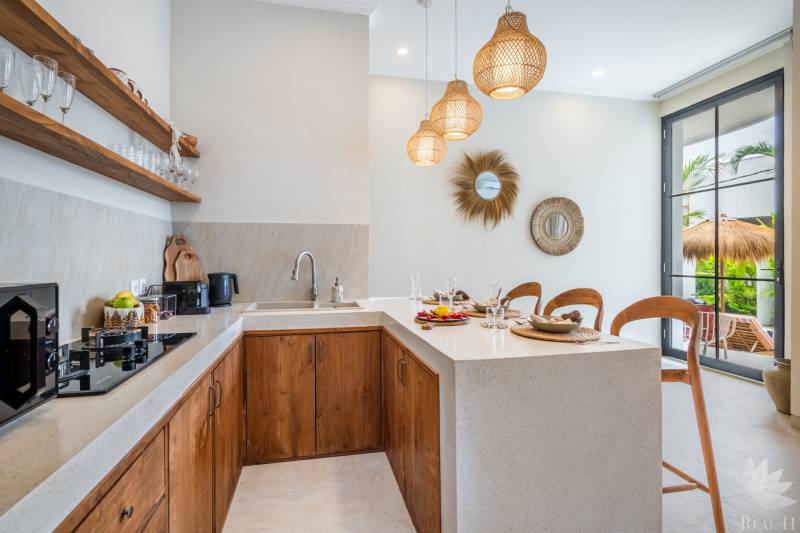 Interiér vily s kuchyňským koutem, dřevěnými skříňkami a dekorativními zrcadly.