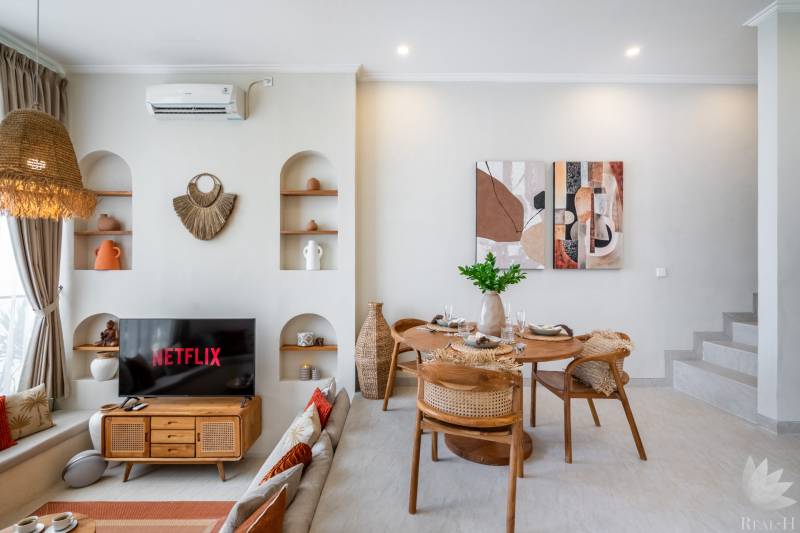 Obývací pokoj vily s televizí, jídelním stolem a dekorativními prvky na stěnách.