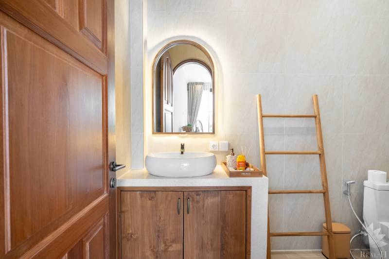 Koupelna ve vile se zrcadlem, umyvadlem a žebříkem jako dekorací.