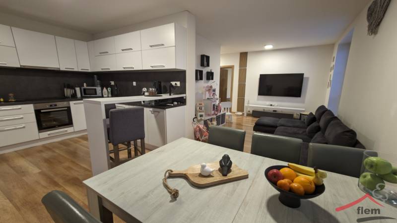 Kuchyně s obývacím pokojem ve 2-pokojovém bytě, světlá linka, podlaha s dřevěným dekorem.