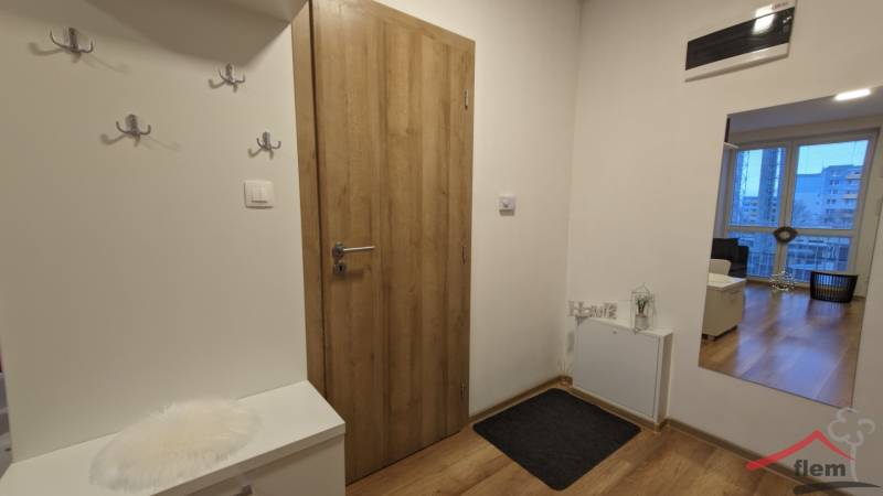 Vstupní chodba v 2-pokojovém bytě, podlaha s dřevěným dekorem a praktické věšáky.