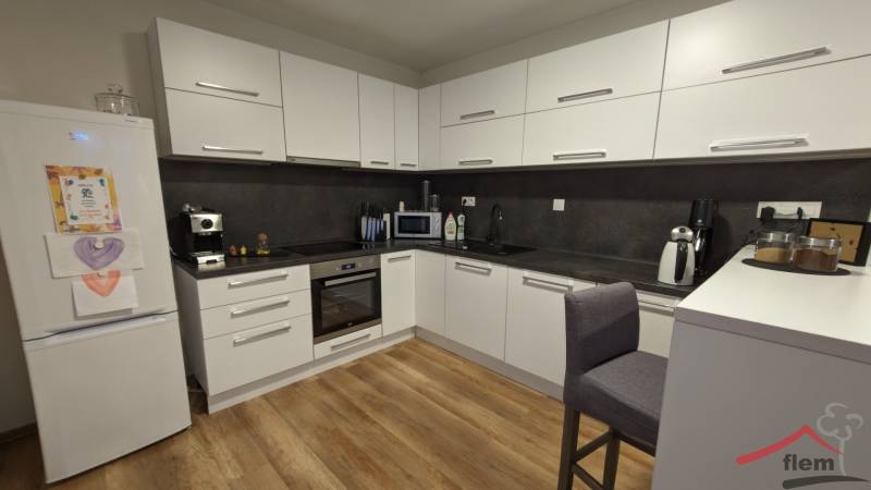 Kuchyně v 2-pokojovém bytě s podlahou s dřevěným dekorem a bílými skříňkami.