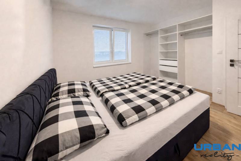 Ložnice v 3-pokojovém bytě s vestavěnou skříní a podlahou s dřevěným dekorem.