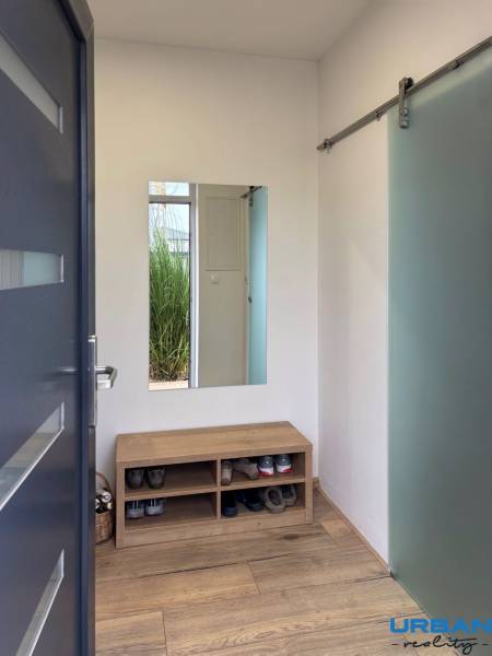 3pokojový byt s lavicí na boty, zrcadlem a podlahou s dřevěným dekorem.