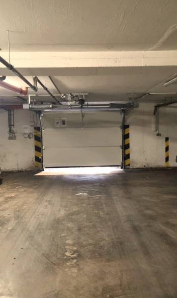 Budova garáže s betonovou podlahou a garážovými vraty.