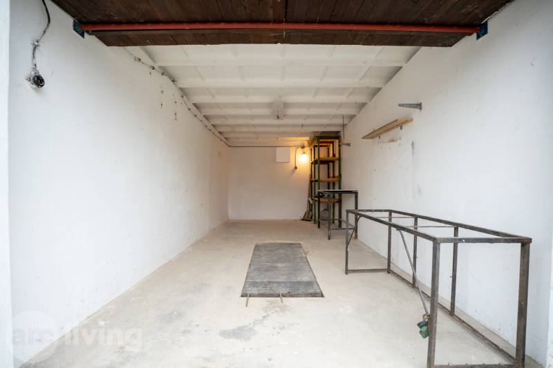 Prostorný interiér garáže s kovovými policemi a bílými stěnami.