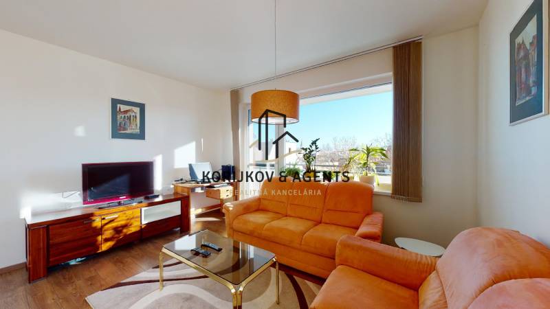 Obývací pokoj v 2-pokojovém bytě s oranžovou sedačkou a TV, podlaha s dřevěným dekorem.