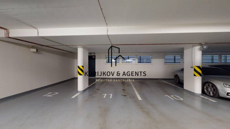 Podzemní garáž s parkovacími místy a sloupy v budově na Strojárenské v Košicích.