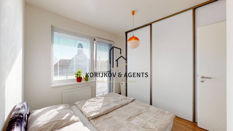 Ložnice s posuvnou skříní a postelí v 2pokojovém bytě, podlaha s dřevěným dekorem.