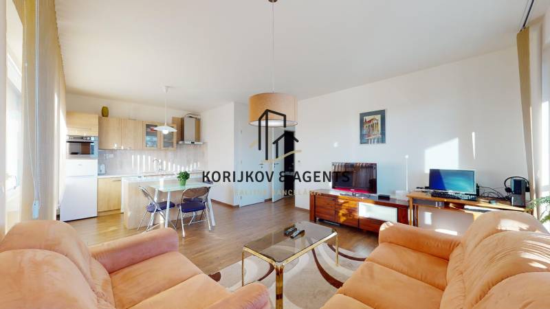 Obývací pokoj s kuchyňským koutem, pohovkami a podlahou s dřevěným dekorem ve 2pokojovém bytě.