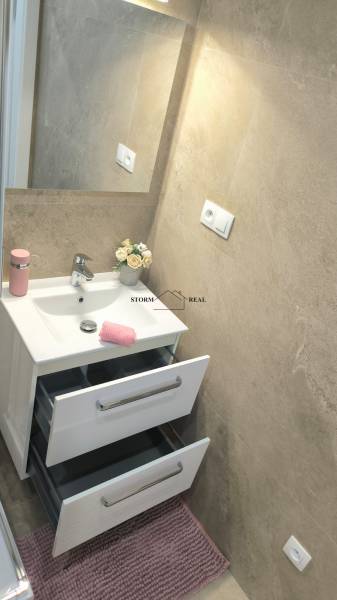 Koupelna se zrcadlem, umyvadlem a skříňkami ve 4-pokojovém bytě.