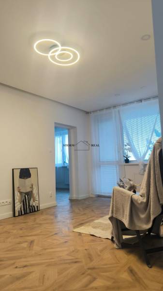 Interiér 4-pokojového bytu s podlahou s dřevěným dekorem a světelným stropním prvkem.