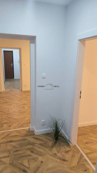 Interiér 4-pokojového bytu s podlahou s dřevěným dekorem a bílými stěnami.