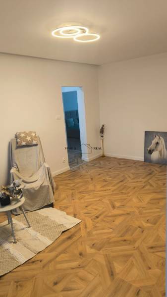 Obývací pokoj se židlí a podlahou s dřevěným dekorem ve 4pokojovém bytě.