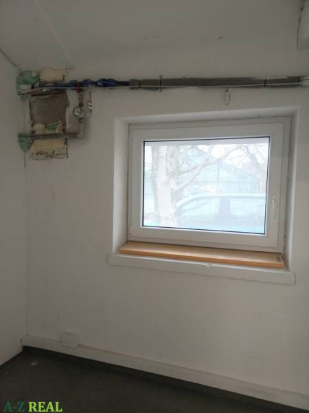 Místnost s oknem a potrubím na stěně ve výrobních prostorách.