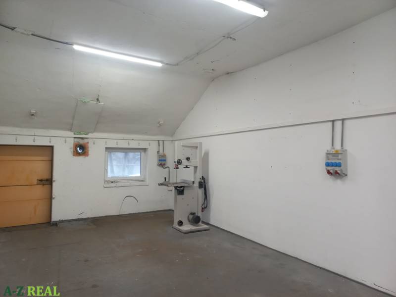 Výrobní prostory s bílými stěnami, nářadím a osvětlením, bez podlahy s dřevěným dekorem.