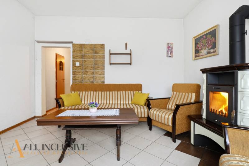 Obývací pokoj v rodinném domě s krbem, pruhovanou sedačkou a konferenčním stolkem.