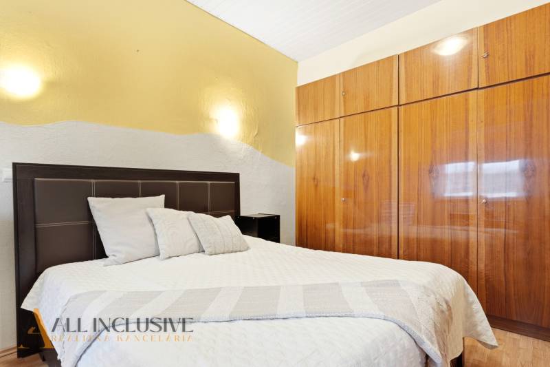 Ložnice s postelí a vestavěnou skříní, Rodinný dům. Neutrální barvy, podlaha s dřevěným dekorem.