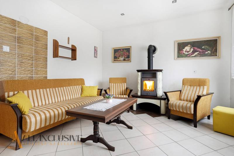 Obývací pokoj v rodinném domě s krbem, pohovkou a dřevěným stolem.