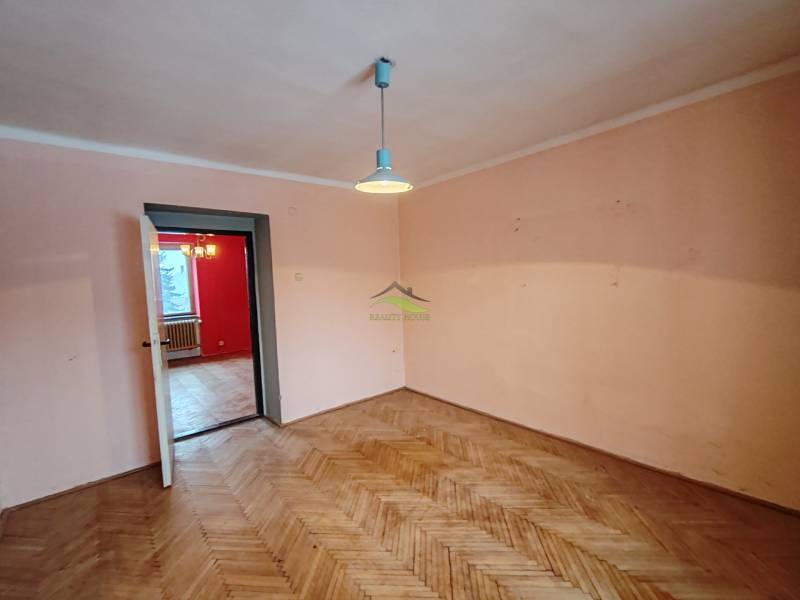 Pokoj v 2-pokojovém bytě s podlahou s dřevěným dekorem a jednoduchým osvětlením.