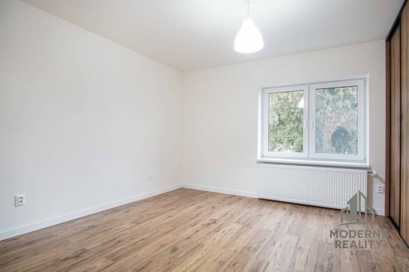 Pokoj v rodinném domě s elektrickými zásuvkami a podlahou s dřevěným dekorem.