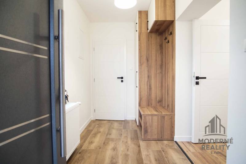 Interiér rodinného domu s podlahou s dřevěným dekorem a vestavěným nábytkem.