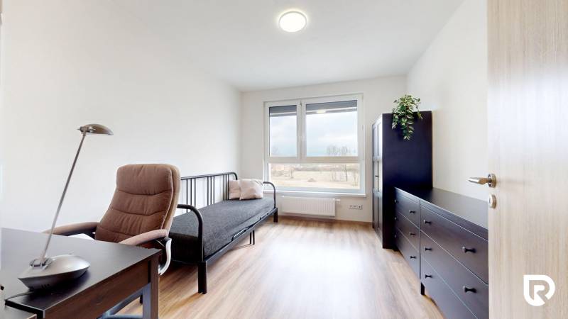 Pokoj s podlahou s dřevěným dekorem, pracovním stolem a pohovkou ve 3-pokojovém bytě.