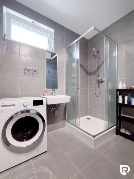 Koupelna v 3-pokojovém bytě s pračkou, sprchovým koutem a umyvadlem.