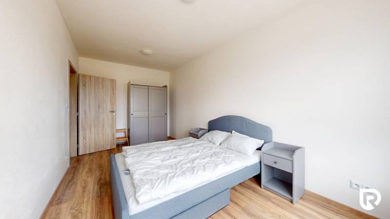 Ložnice v 3-pokojovém bytě s podlahou s dřevěným dekorem, šedou postelí a šatníkem.