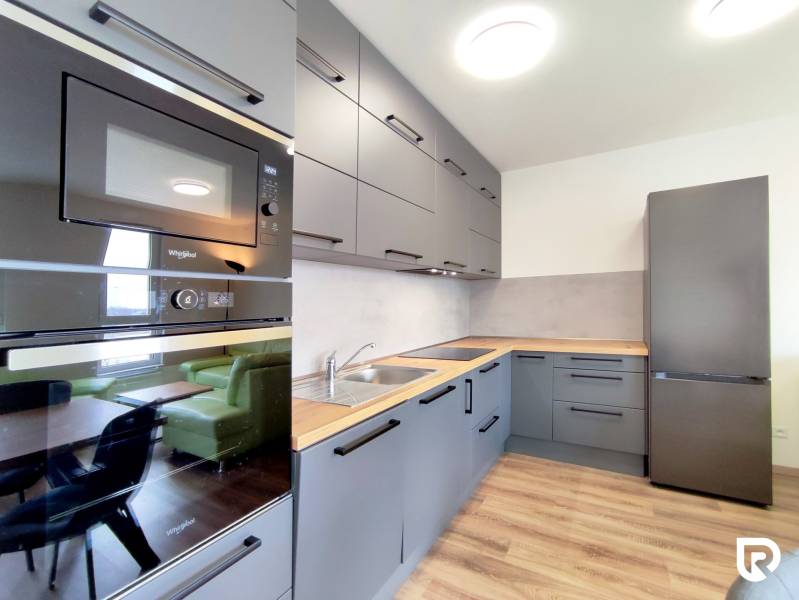 Kuchyně ve 3-pokojovém bytě s podlahou s dřevěným dekorem, šedé skříňky, vestavěné spotřebiče.