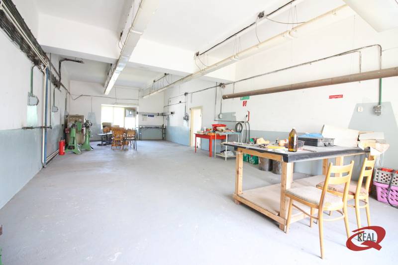 Průmyslový interiér budovy s pracovním stolem a židlemi.