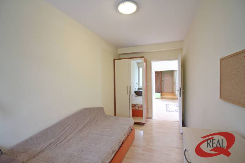 Pokoj v 3-pokojovém bytě s pohovkou, vestavěnou skříní a podlahou s dřevěným dekorem.