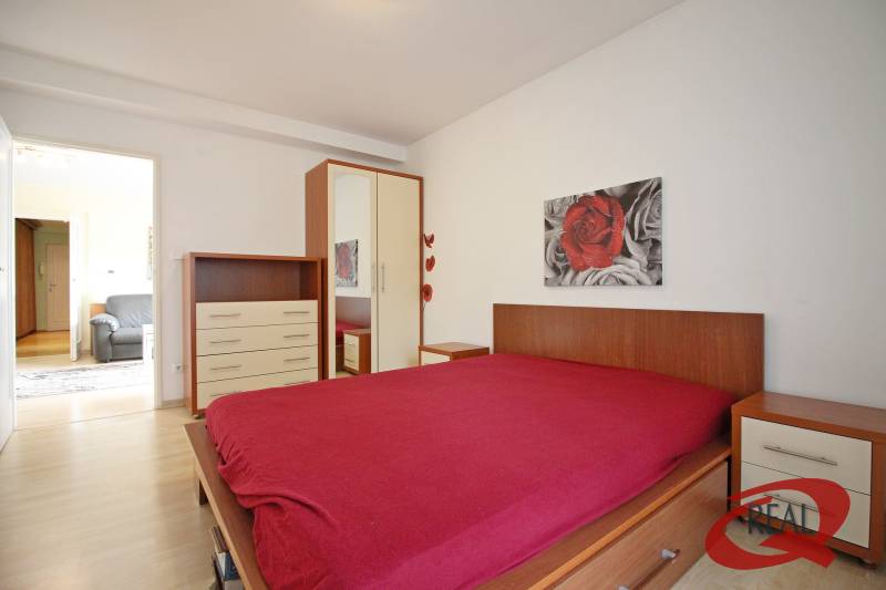 Ložnice s podlahou s dřevěným dekorem, postelí, skříňkou a obrazem v 3-pokojovém bytě.