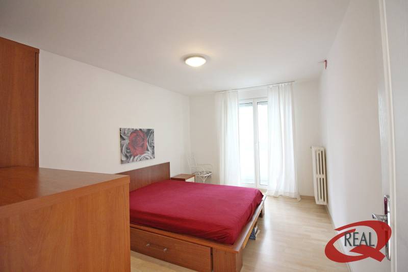 Ložnice v 3-pokojovém bytě s postelí a podlahou s dřevěným dekorem.