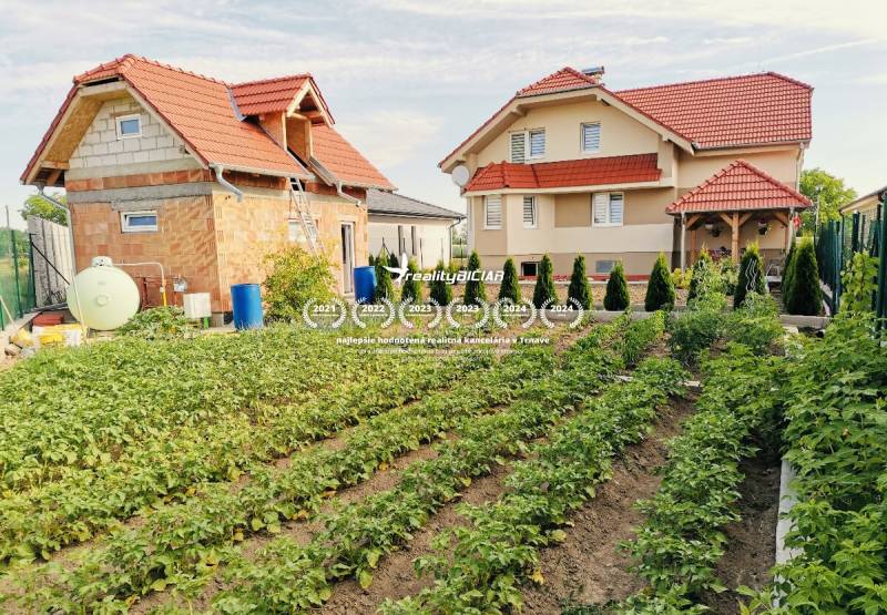 Rodinný dům v Ratkovcích s prostornou zahradou plnou zeleniny a stromů.