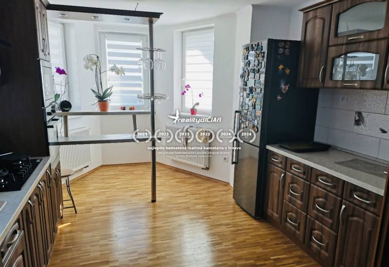 Kuchyně v rodinném domě s podlahou s dřevěným dekorem, tmavým nábytkem a barovým pultem.