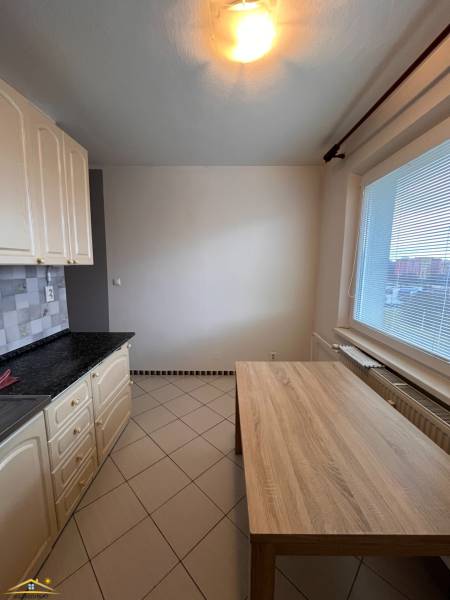 Kuchyně v 2-pokojovém bytě s keramickou dlažbou a jídelním stolem.