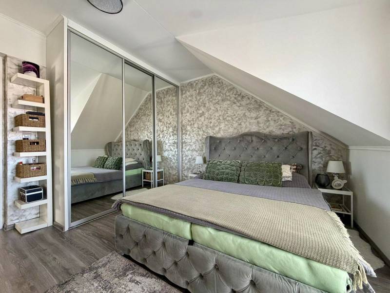 Interiér 2-pokojového bytu s podlahou s dřevěným dekorem, šikmým stropem a zrcadlovou skříní.