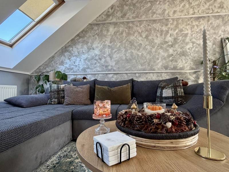 Obývací pokoj v 2-pokojovém bytě s dekorativními polštáři na pohovce a svíčkami na stole.