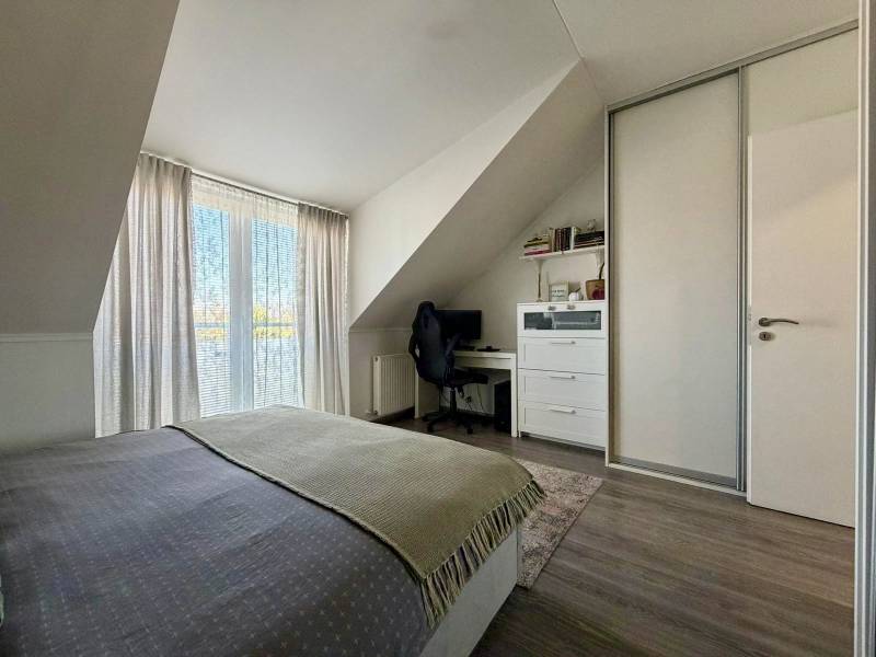 Ložnice v 2pokojovém bytě s pracovním stolem a podlahou s dřevěným dekorem.