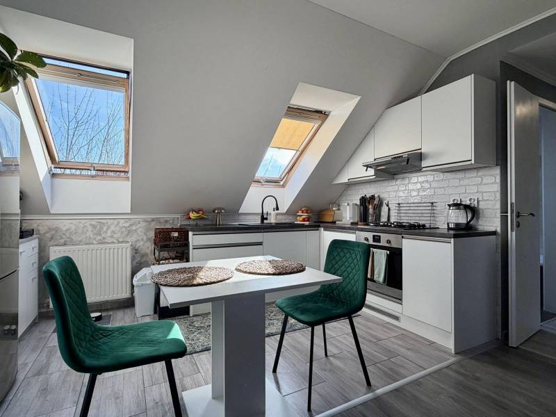 Kuchyně v 2-pokojovém bytě s podlahou s dřevěným dekorem a stolem se židlemi.